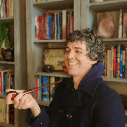 Matthew Distefano holding a pipe in front of a bookcase. 